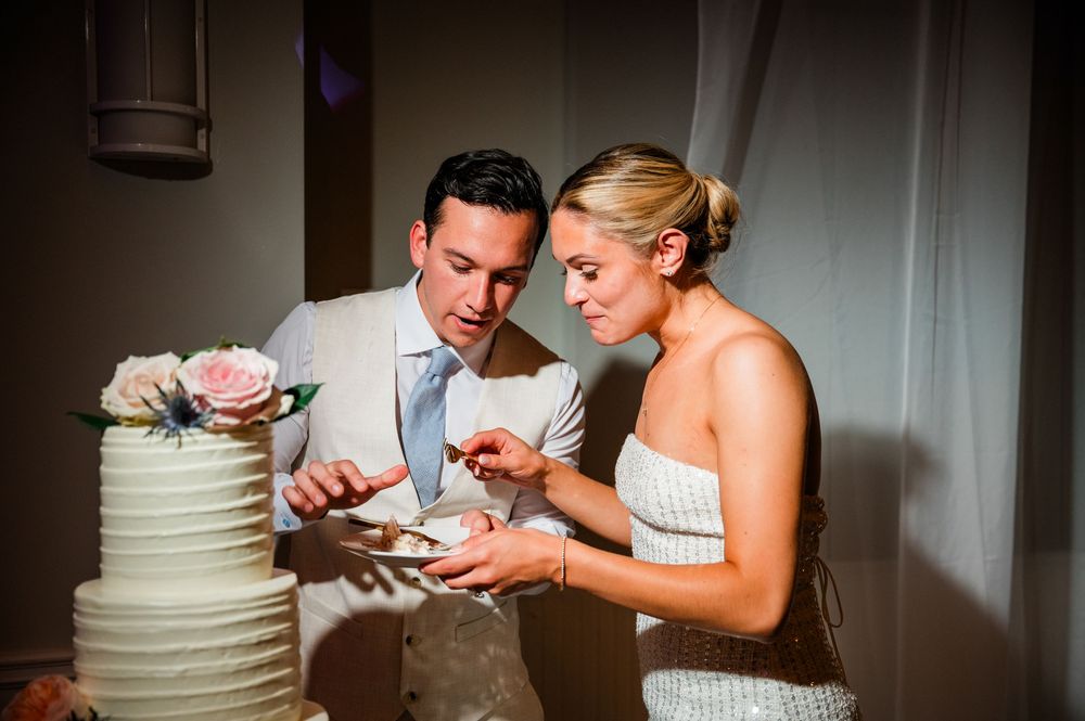A couple shares a bite of wedding cake together during their reception celebration.