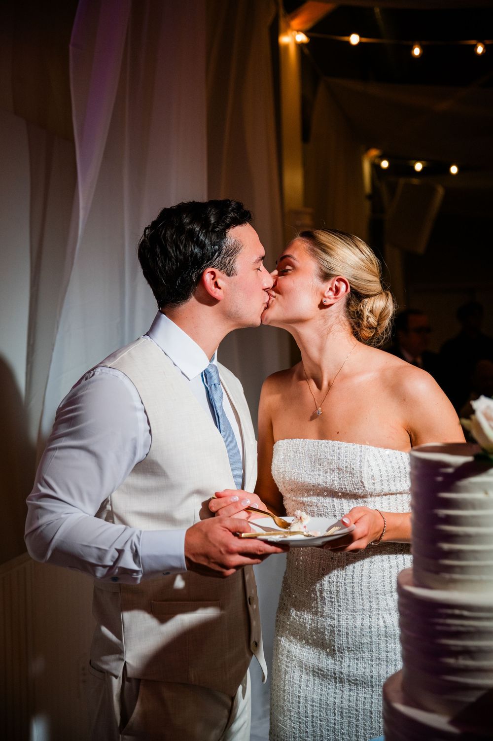A couple shares a sweet moment while cutting their wedding cake at the reception.