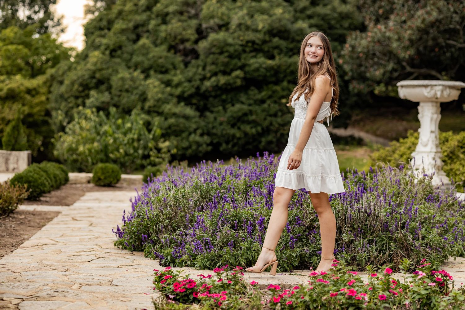 A garden pathway lined with blooming purple lavender and pink roses creates a romantic outdoor setting.