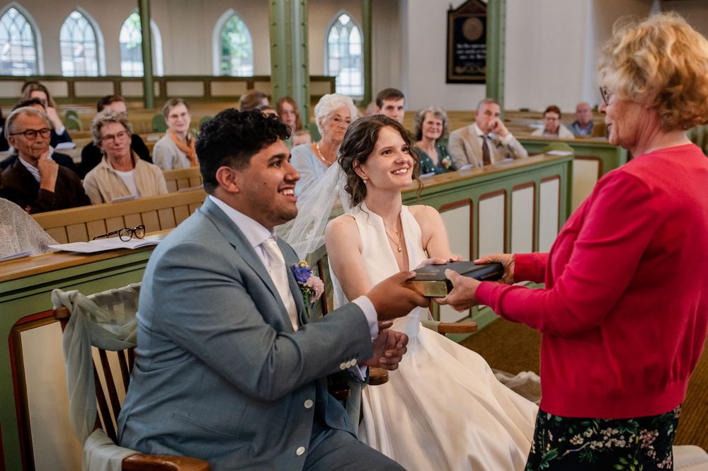 Bijbeloverhandiging aan bruid en bruidegom tijdens evangelische kerkdienst in Huizen