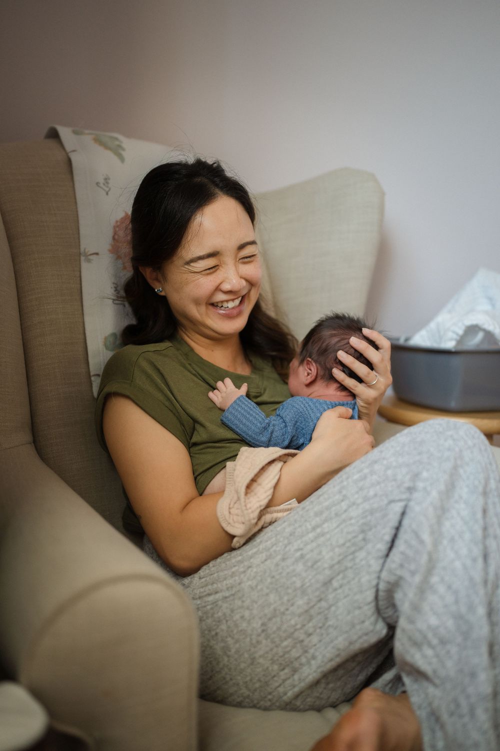 A tender moment between parent and newborn baby resting together on a cozy chair.