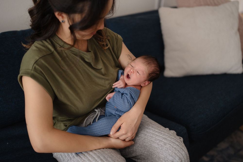 Tender moments shared on a navy blue couch during a relaxed indoor photo session.