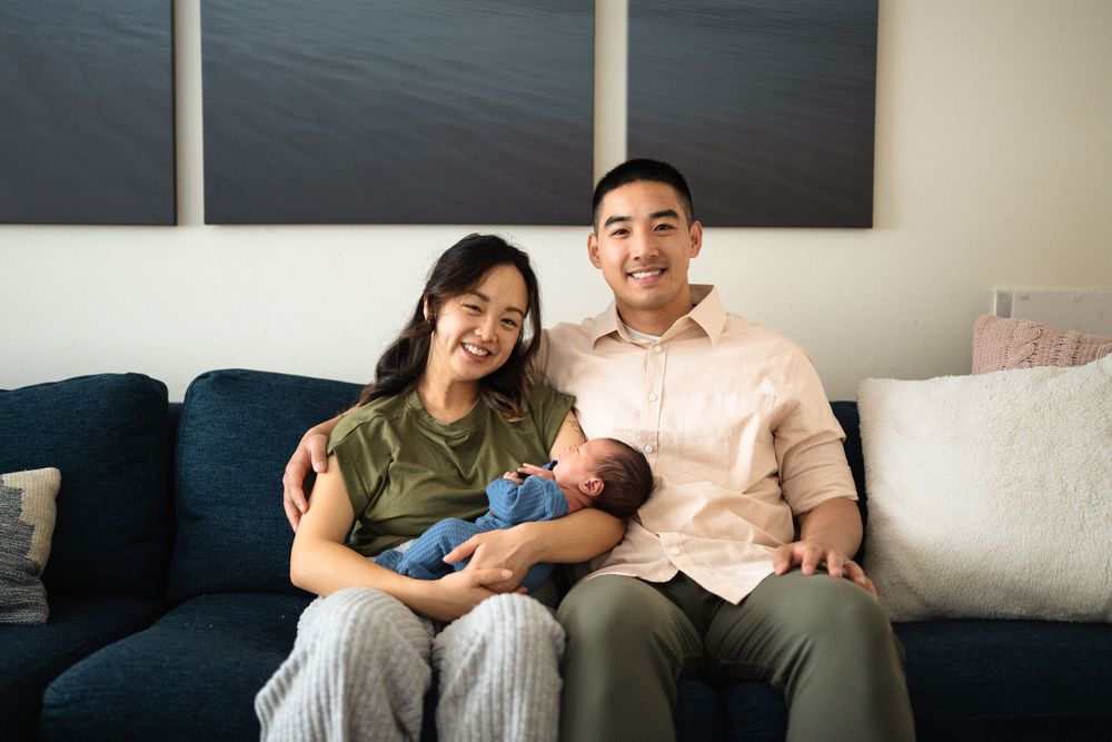 Family relaxing together on blue couch during lifestyle photoshoot.