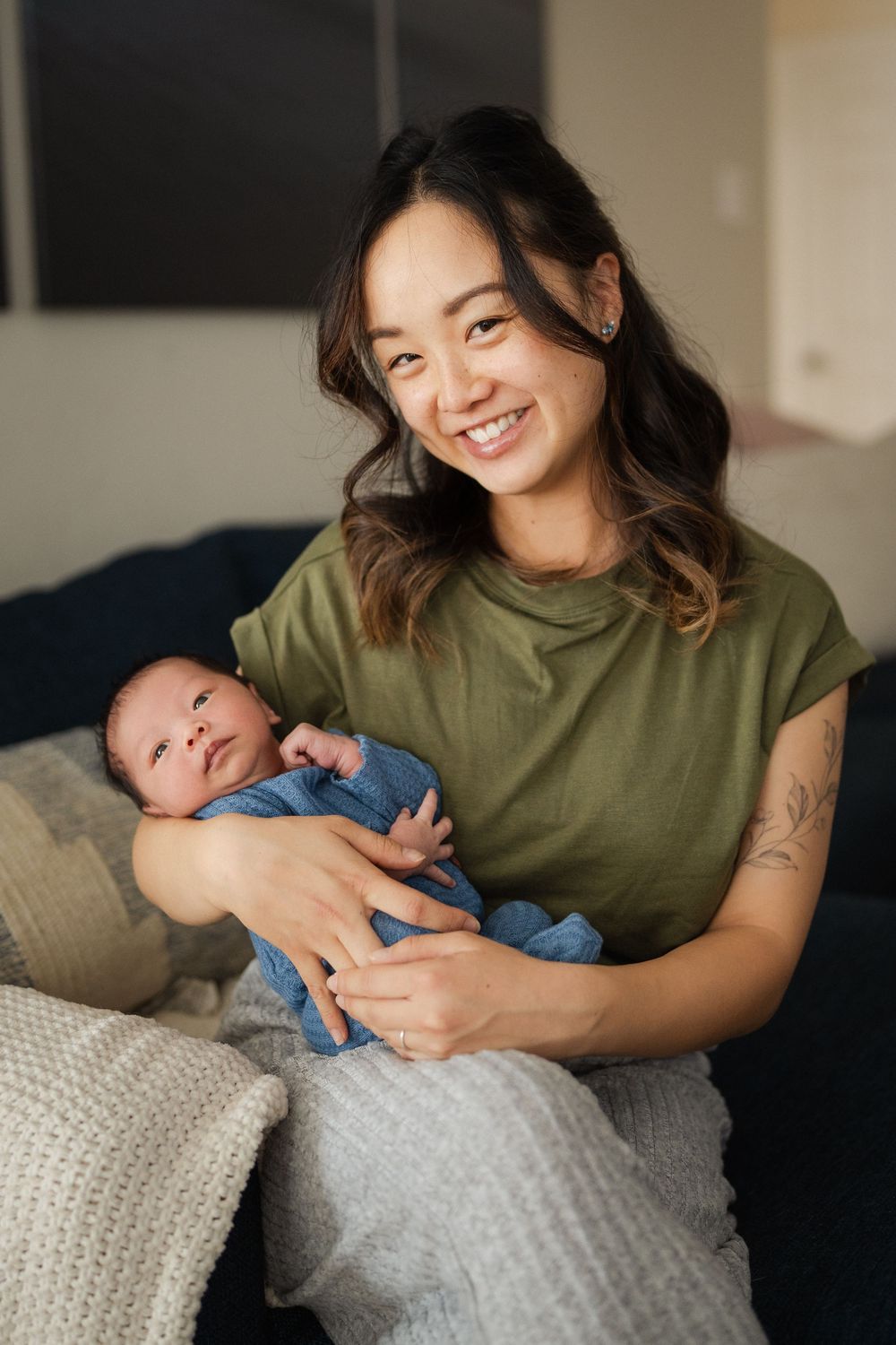 A joyful moment between parent and baby while relaxing on a comfortable couch with throw pillows.