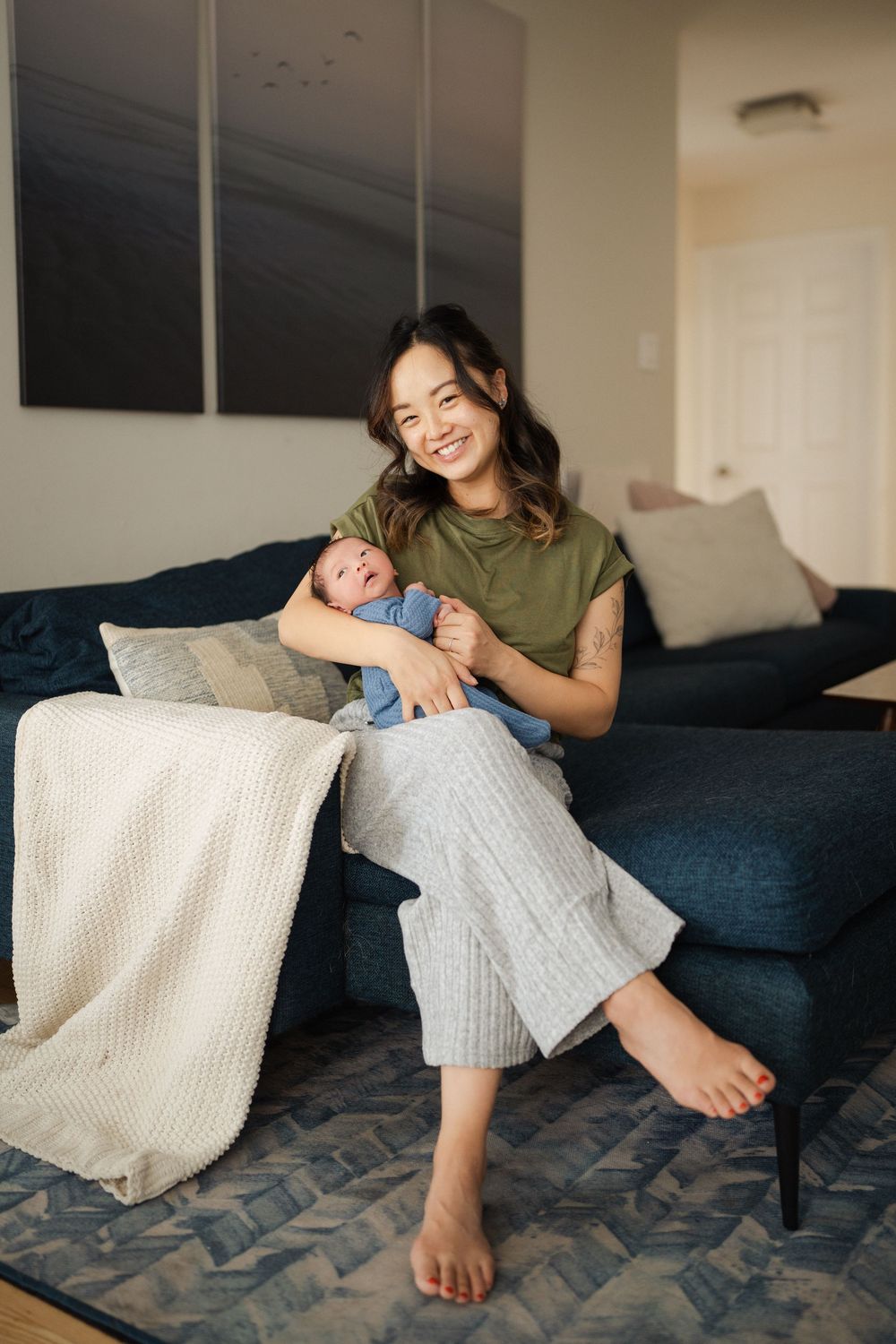 Relaxed moments on a navy couch with white throw blanket showing intimate parent-child bonding time.