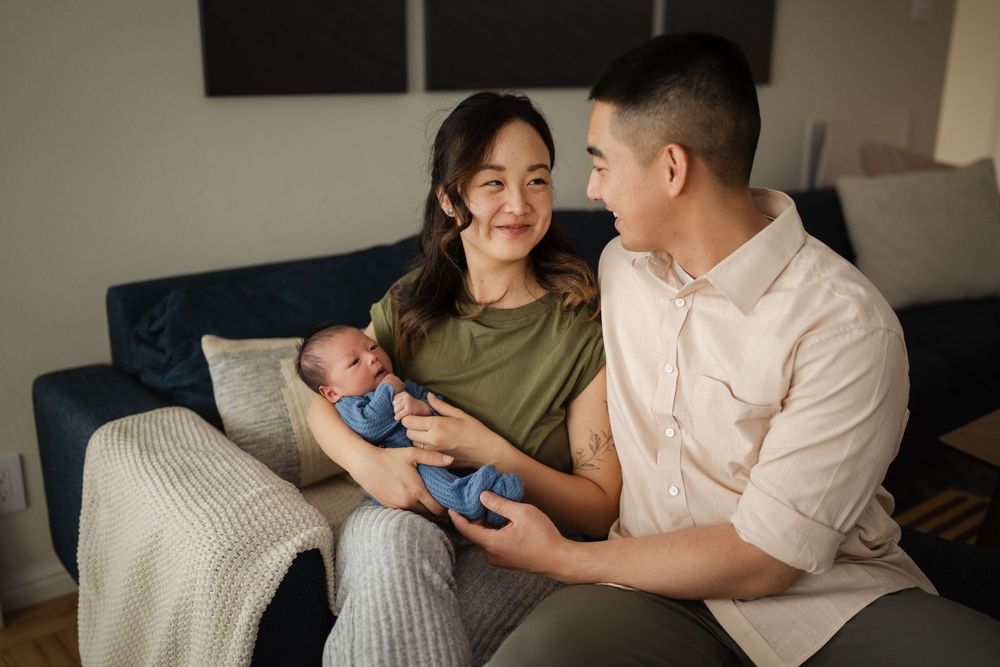 A couple sits close together on a couch playing with something blue in their hands during an intimate moment.