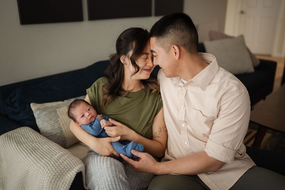 Parents and newborn sharing intimate moments together in a naturally lit room.