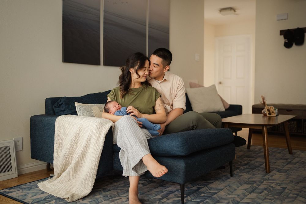 A family shares a loving moment together on their blue couch in a modern living room setting.