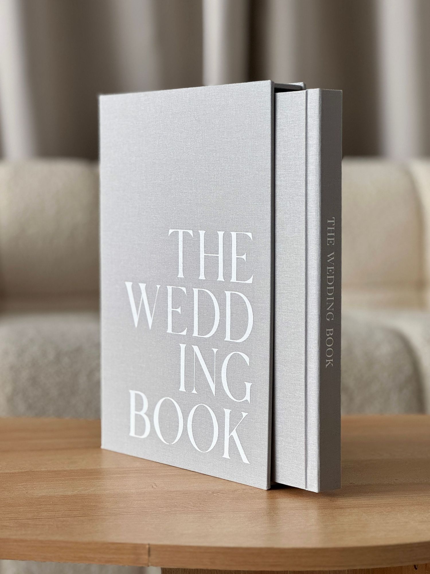 Multiple gray hardcover books with white typography stacked on a wooden surface.