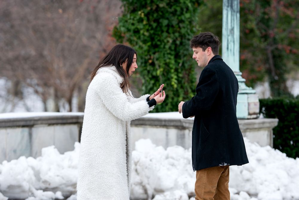 Couple exchanging rings during a heartfelt winter marriage proposal surrounded by snow in an outdoor park.