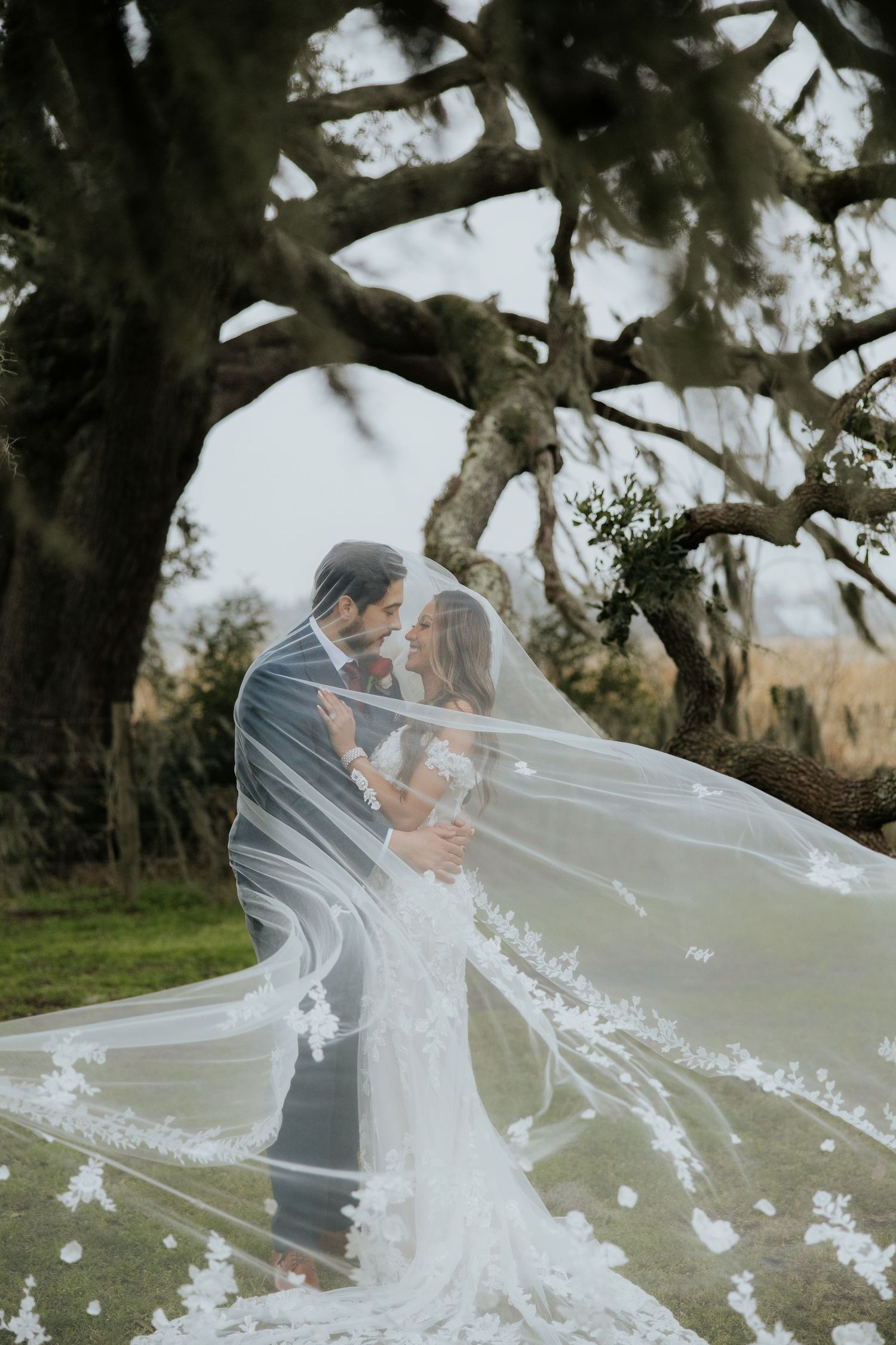 Romantic wedding portrait with bride's veil flowing dramatically in the wind.