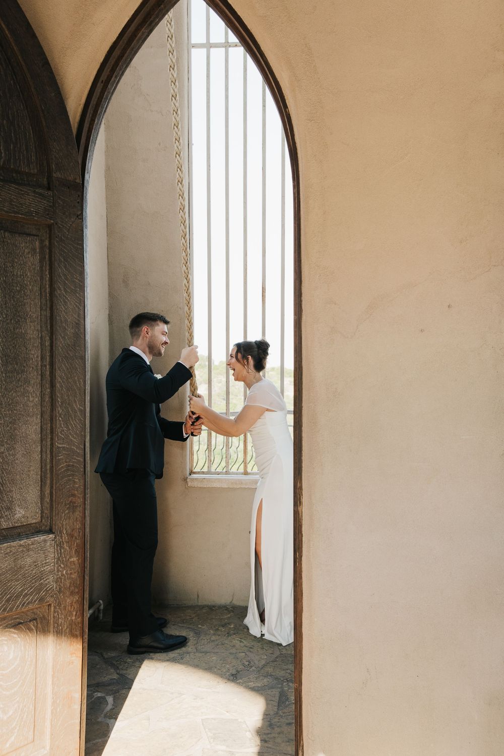 A couple shares an intimate moment in a stone archway on their wedding day.