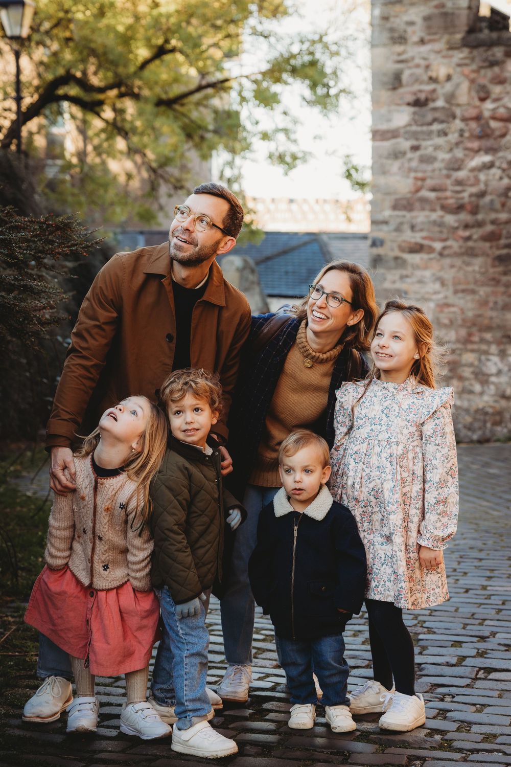 A family shares joyful moments together on a cobblestone street during an outdoor photo session.