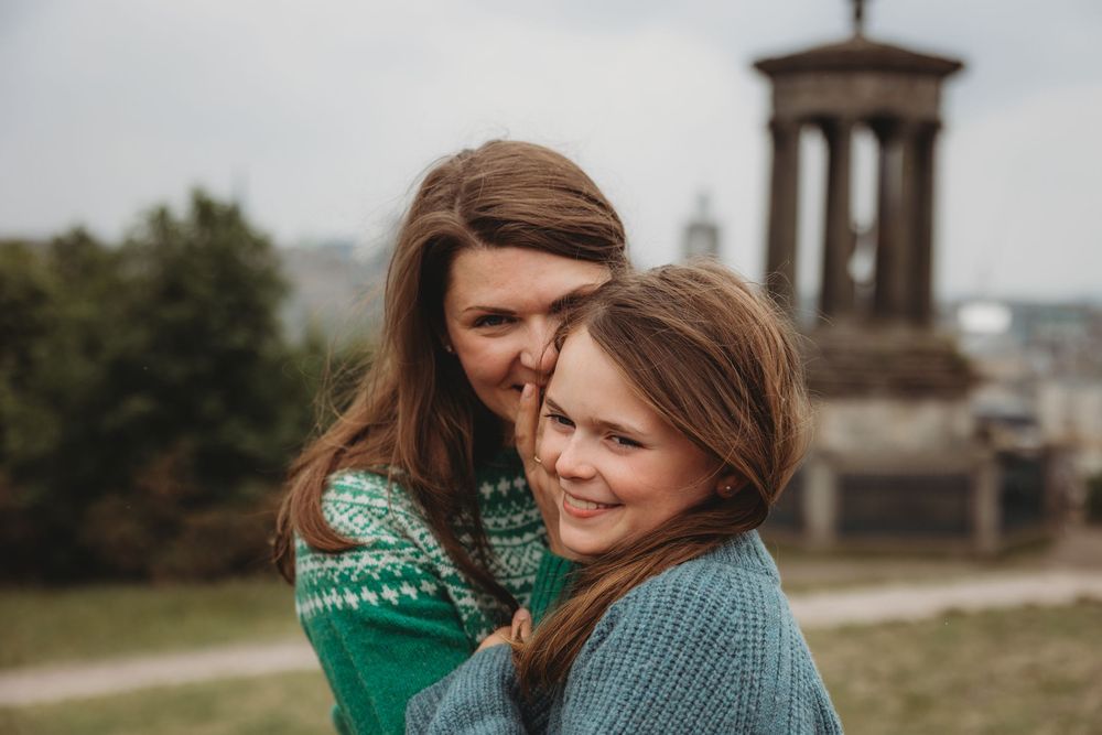Two people in warm sweaters share a joyful moment together outdoors on an overcast day.