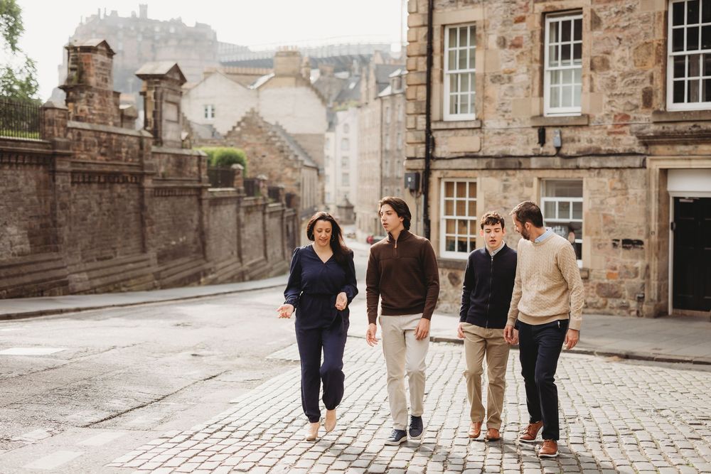 Group walking along charming stone buildings and cobblestone paths in Edinburgh's historic Old Town district.