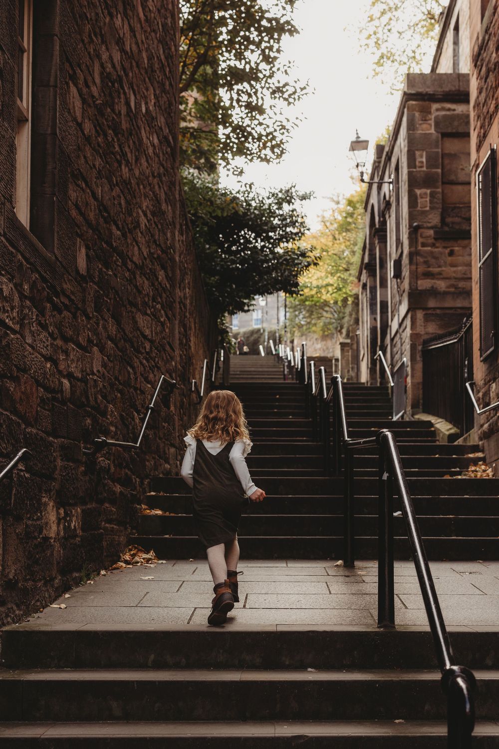 A series of five sequential photos showing someone walking down urban stone steps with a dark brick wall.
