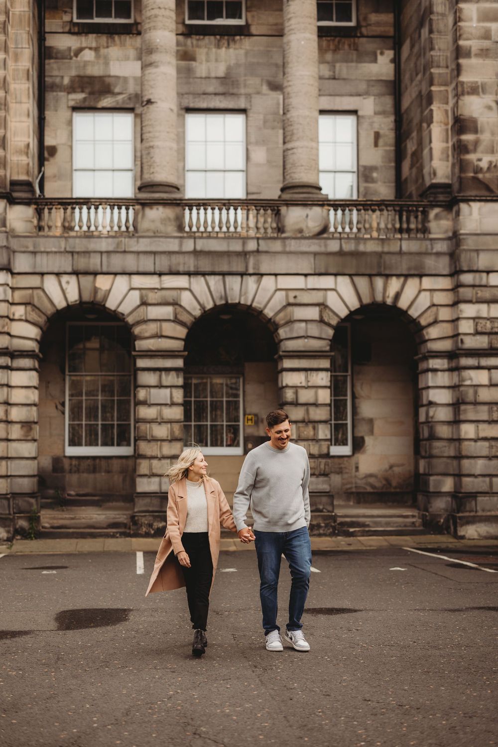 People walking and interacting in a courtyard surrounded by classic stone architecture.