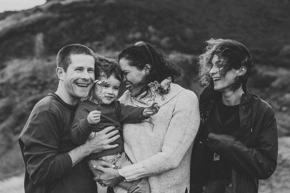 A family shares joyful moments together in a series of black and white outdoor photographs.