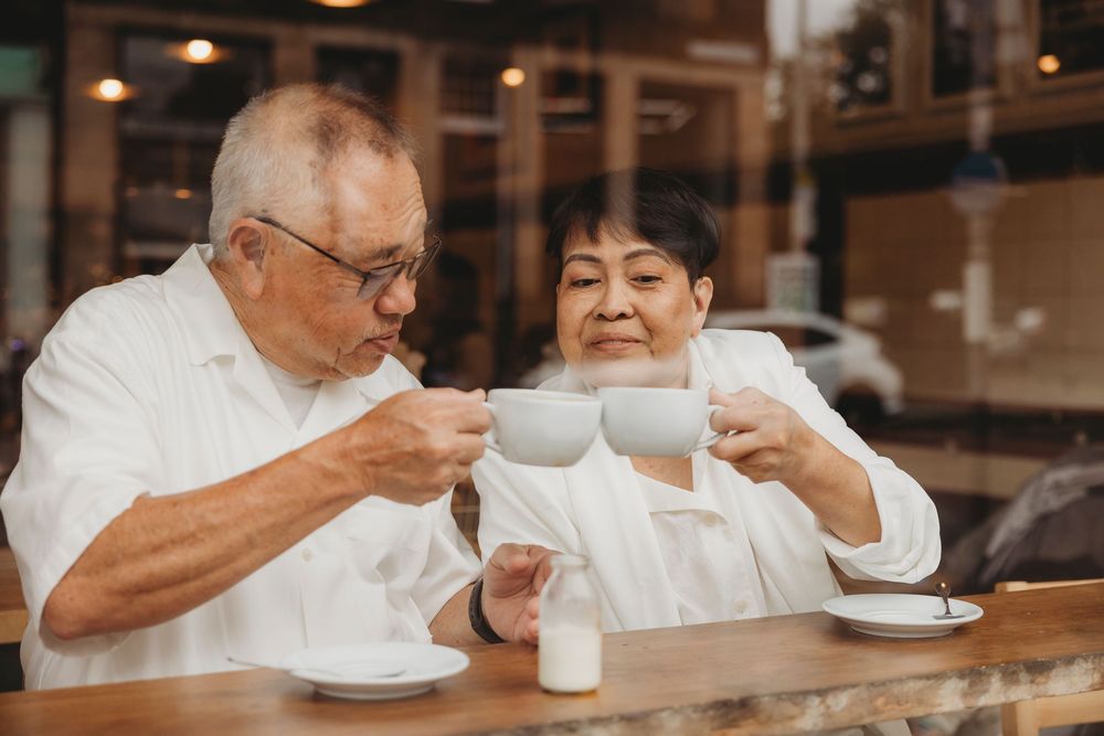 Two people enjoying tea and conversation at a cafe counter through multiple window reflections.