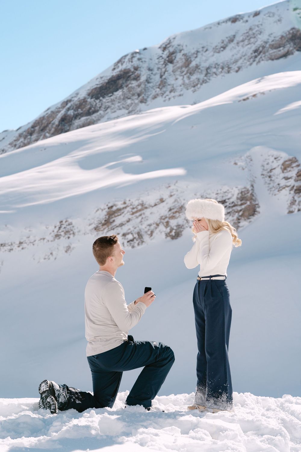 A romantic winter proposal scene in the snowy mountains with two people standing in fresh powder snow in Grindelwald.