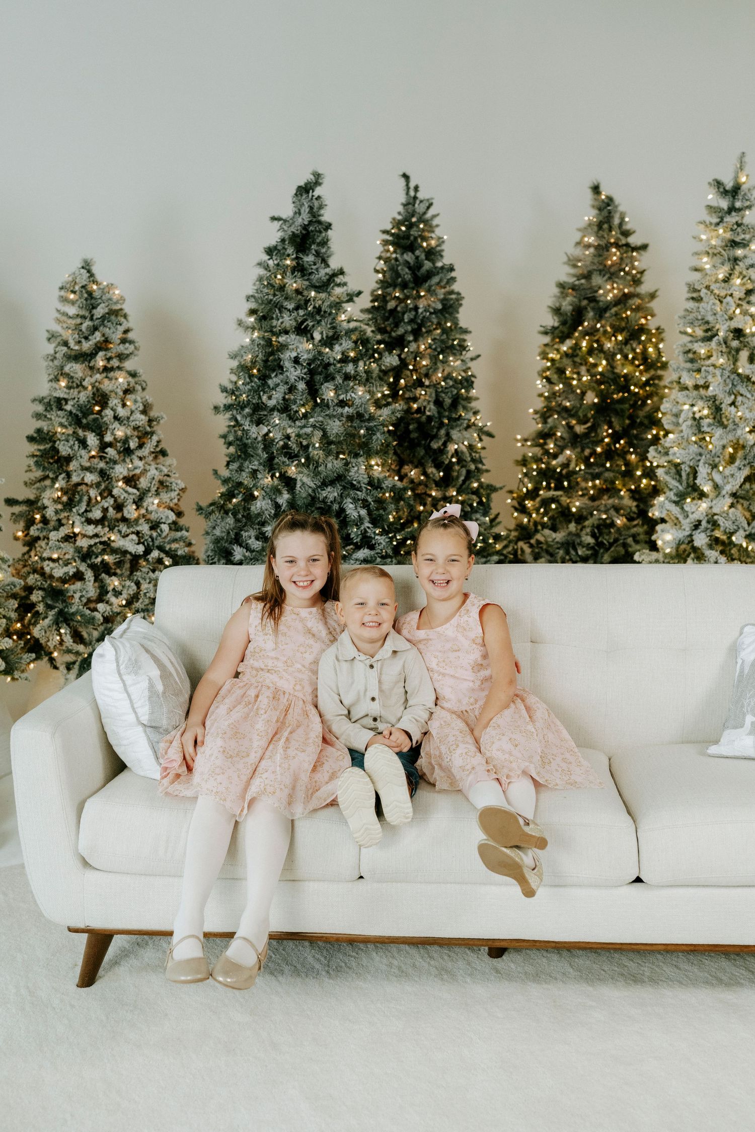 A sequence of four photos showing people sitting on a white couch with decorated Christmas trees in the background.