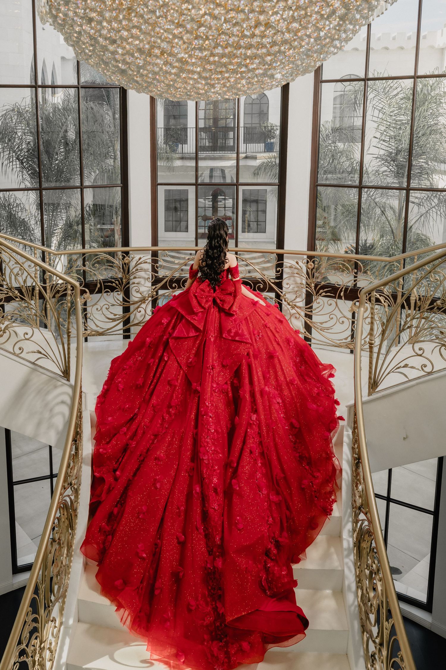 Dramatic red tulle gown displayed under crystal chandeliers in an elegant interior setting.