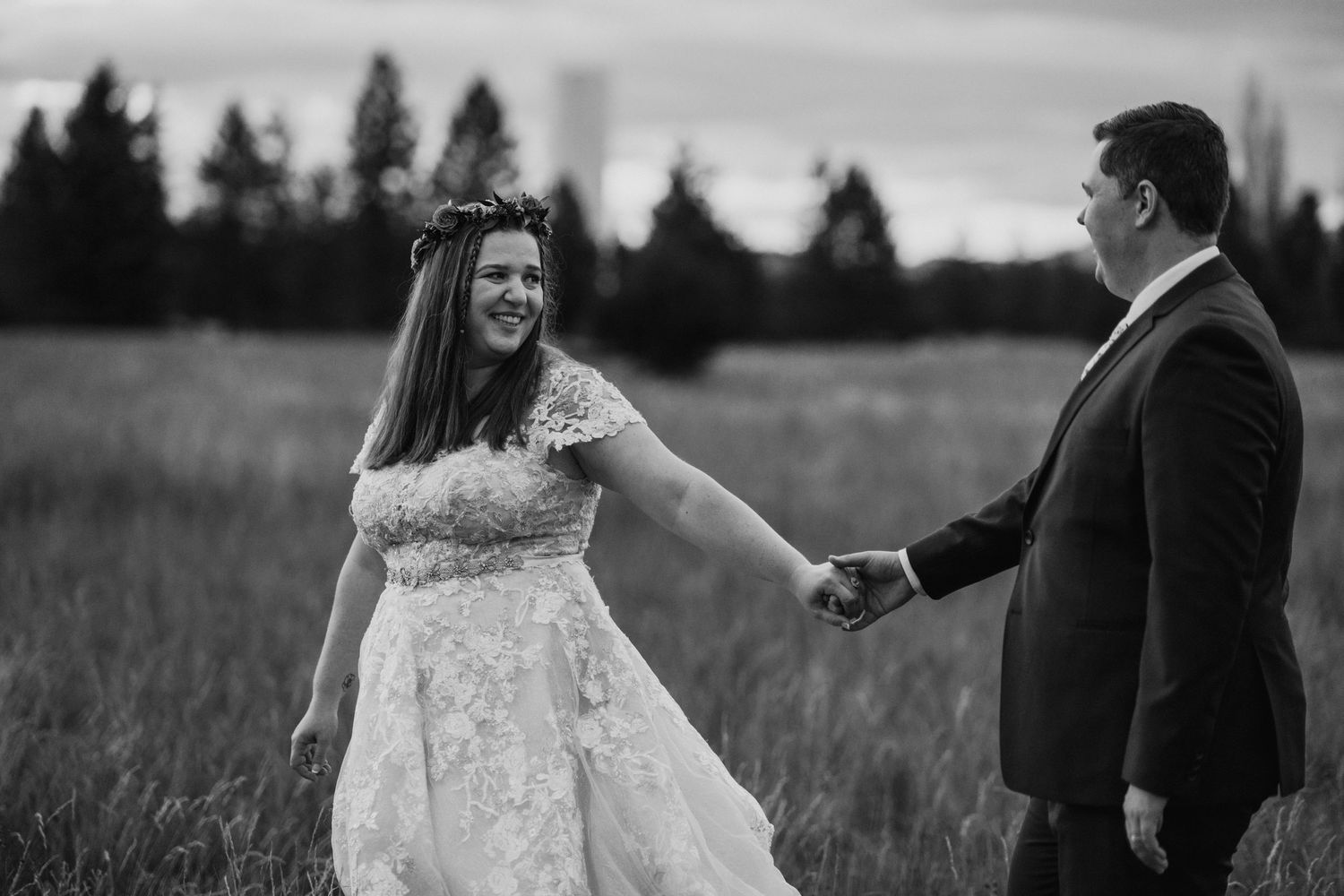A couple shares an intimate moment in a field during their wedding ceremony in black and white.