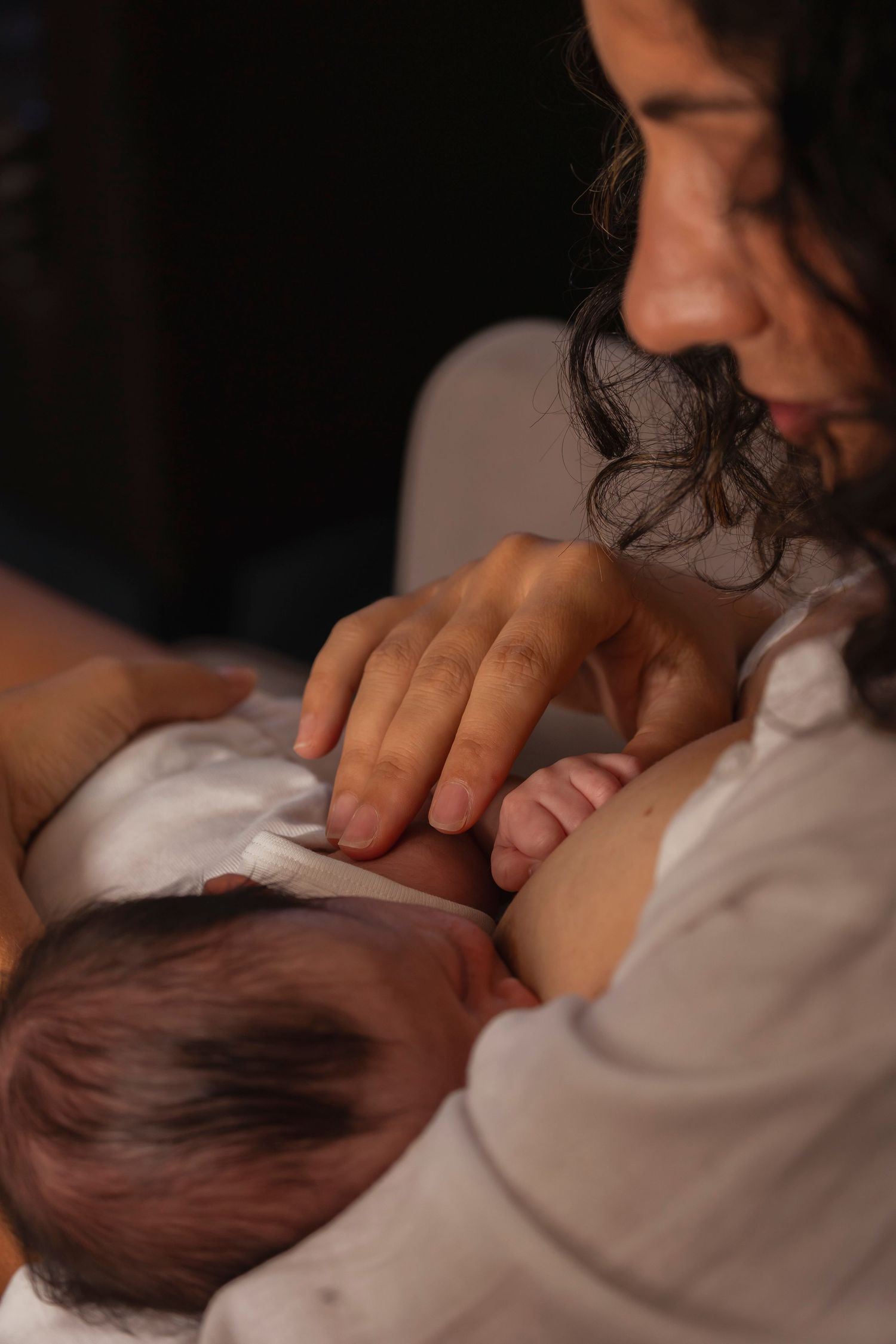 Newborn photography session. Intimate black and white photograph showing tender care and nurturing moments.