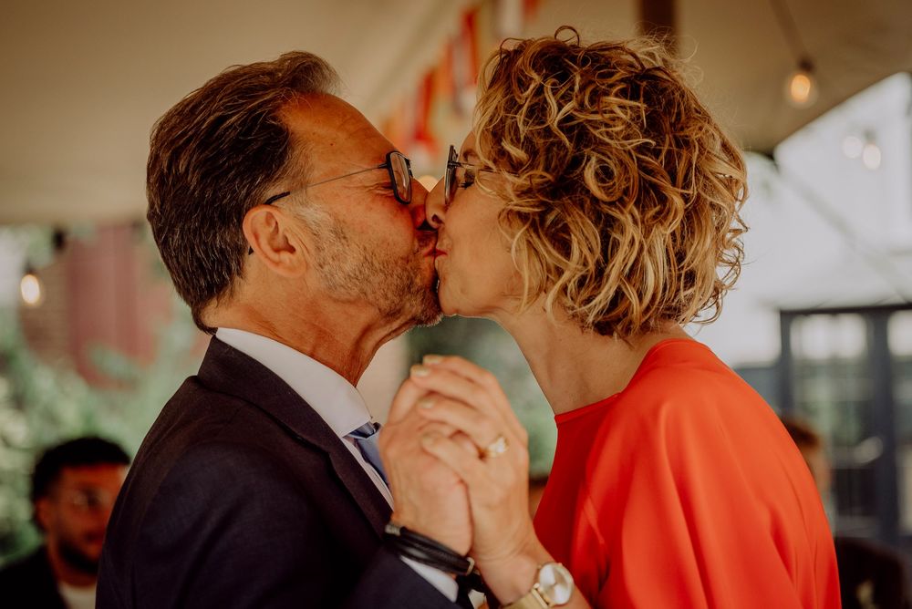 Newlywed couple sharing first kiss at outdoor wedding ceremony under decorated tent.