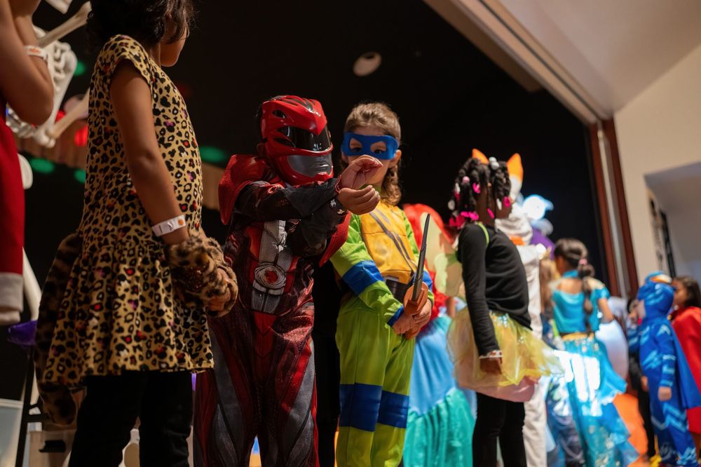 Performers in colorful costumes and masks stand on stage during a show.
