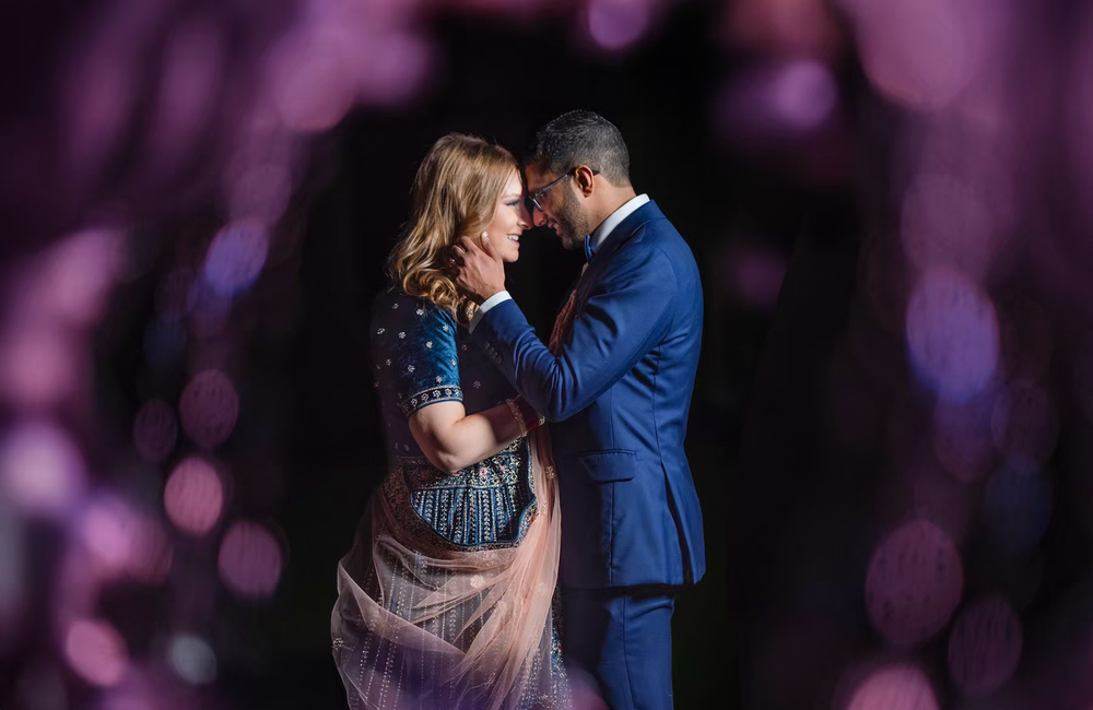 A newlywed couple in formal attire shares an intimate dance moment against a purple-lit bokeh background in Columbus Ohio