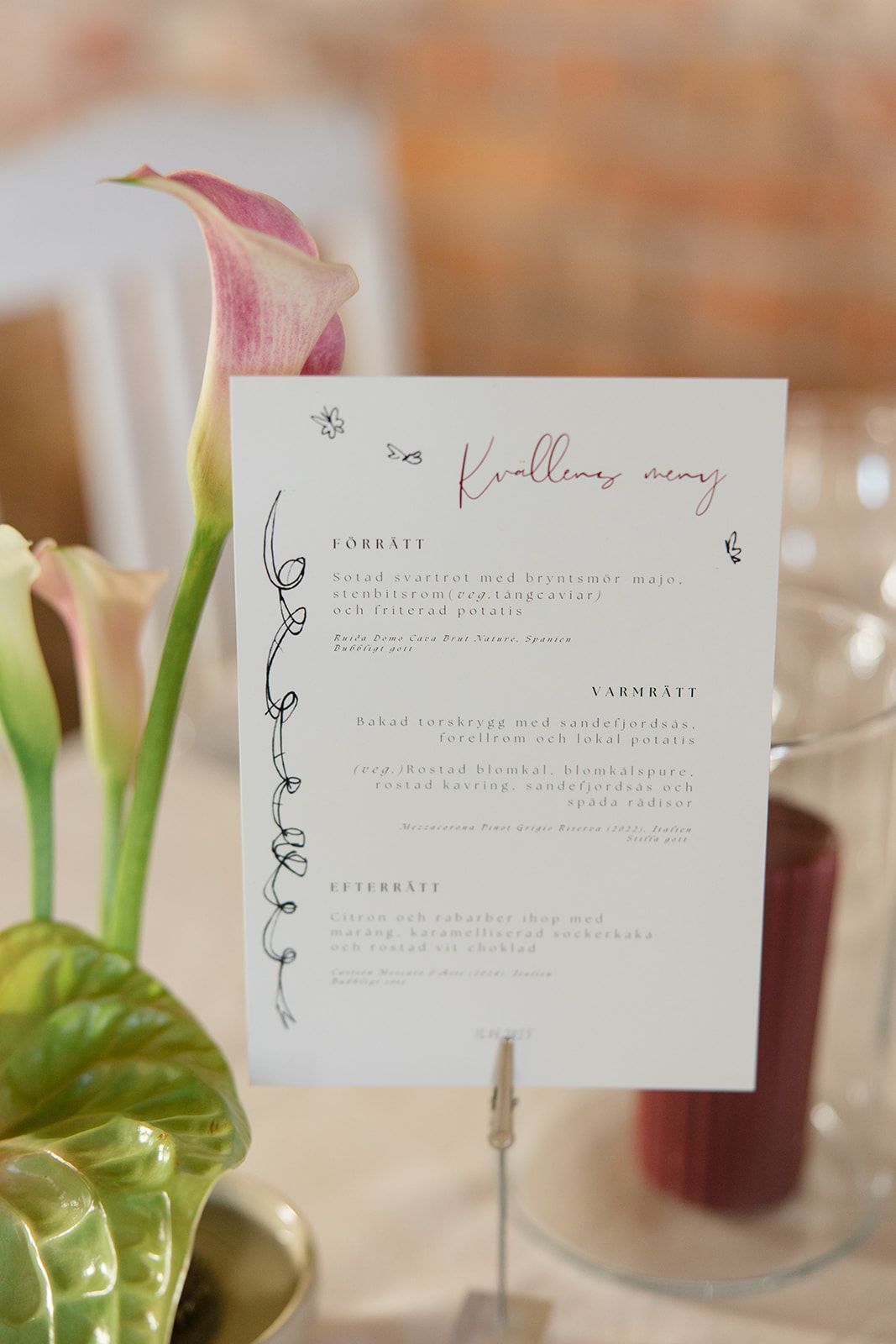 Close-up view of elegant wedding menu cards with minimalist floral illustrations displayed on white table settings.