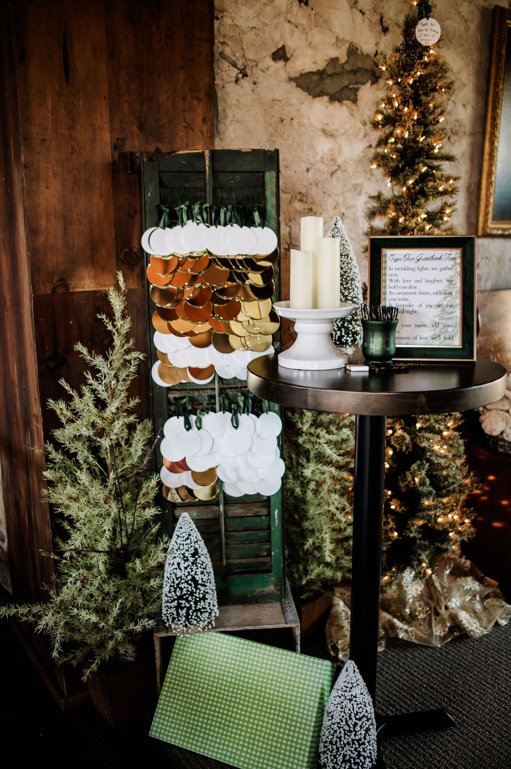 Wedding dessert display with cupcakes and greenery against a dark wood backdrop with twinkling lights.