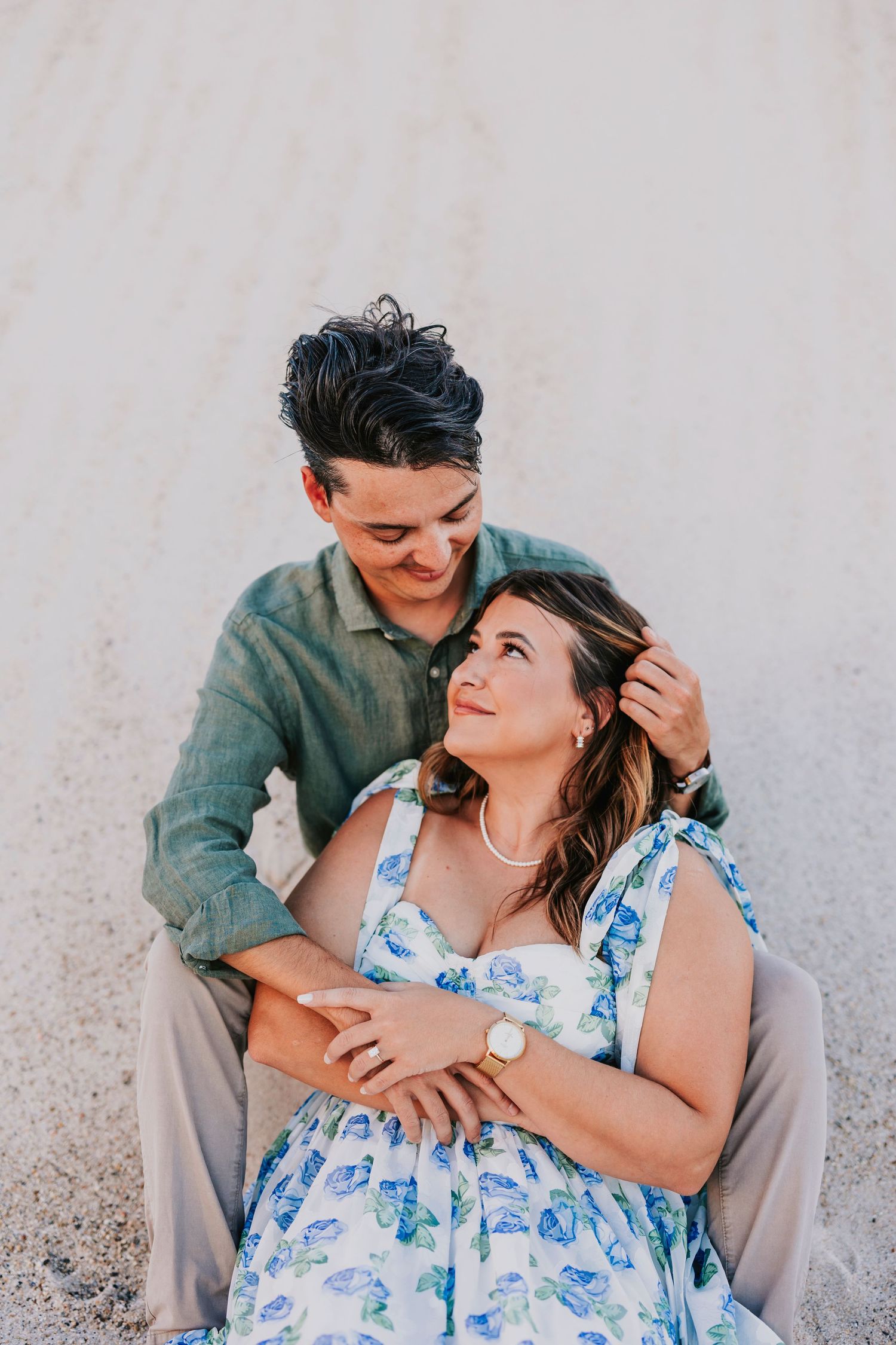 Couple sharing tender moments against white wall in casual attire.