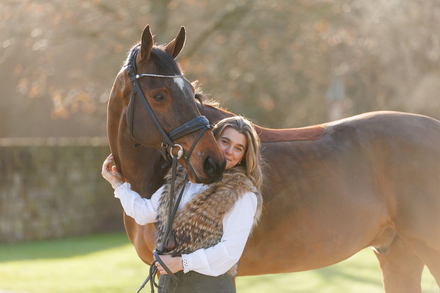 A horse and its rider enjoy an outdoor photoshoot session near rustic wooden fencing on a sunny day.
