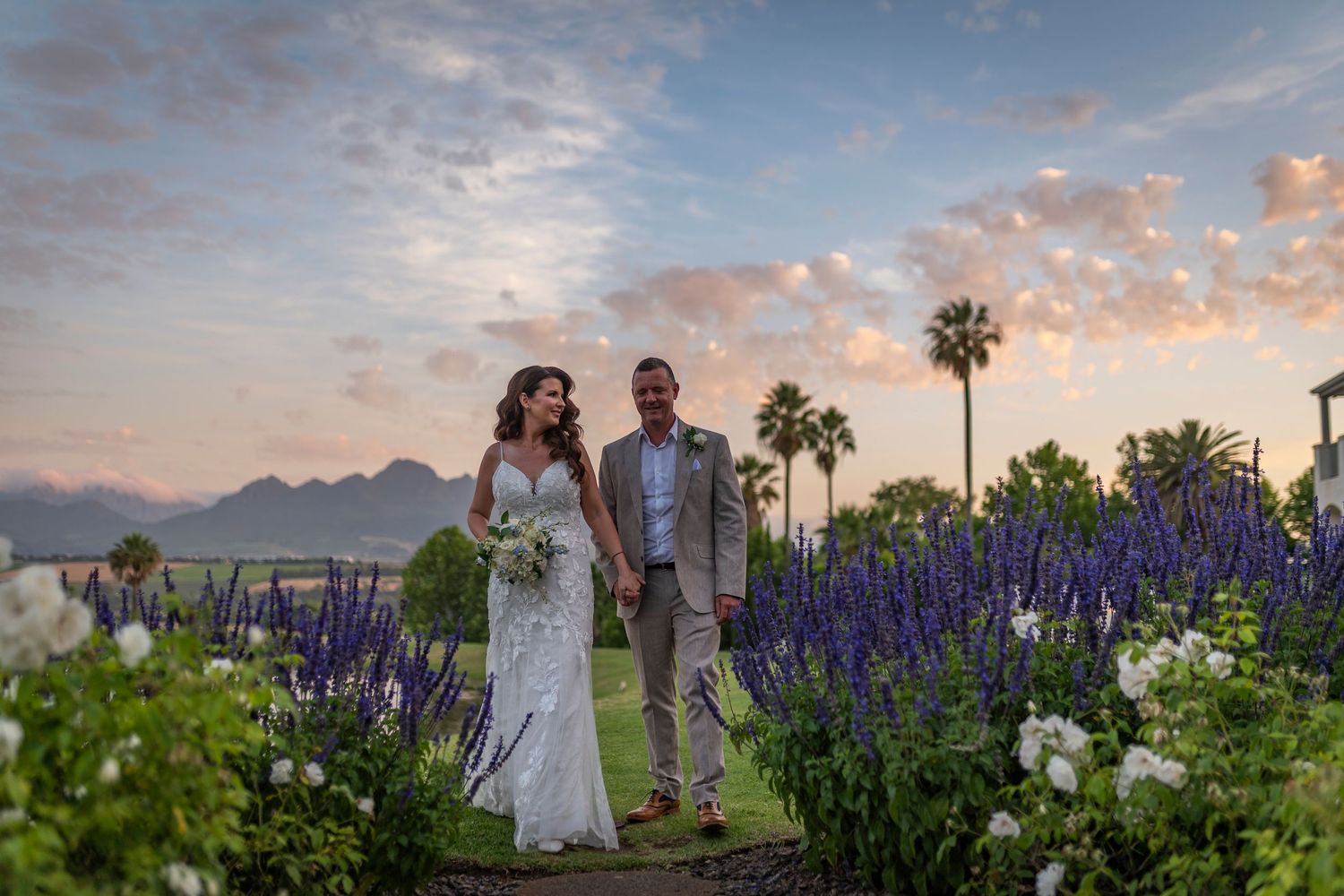 Desert wedding ceremony at sunset with mountains and palm trees in the background.