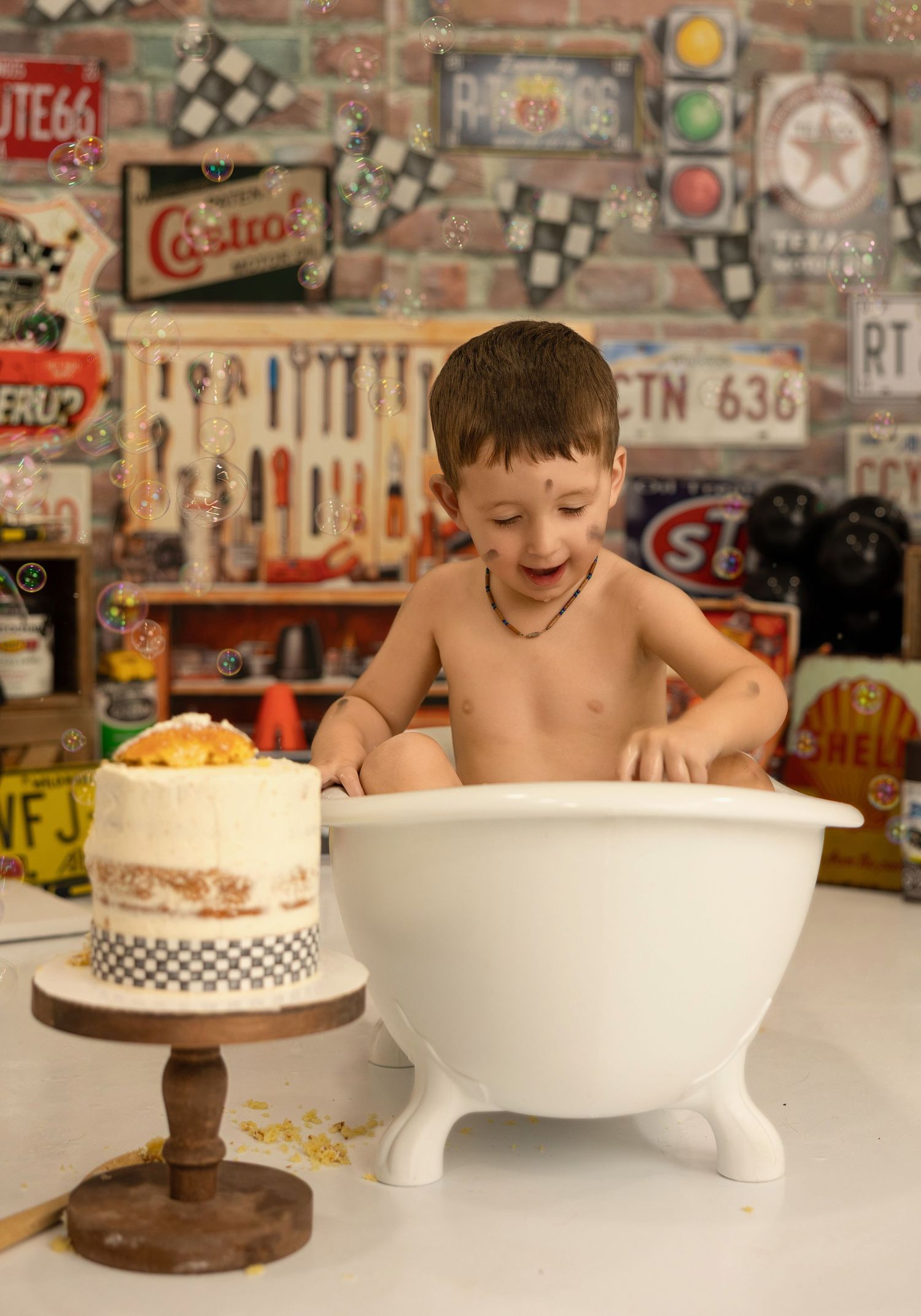 A joyful bath time scene in a retro garage setting with decorative cake and vintage automotive signs on brick wall.