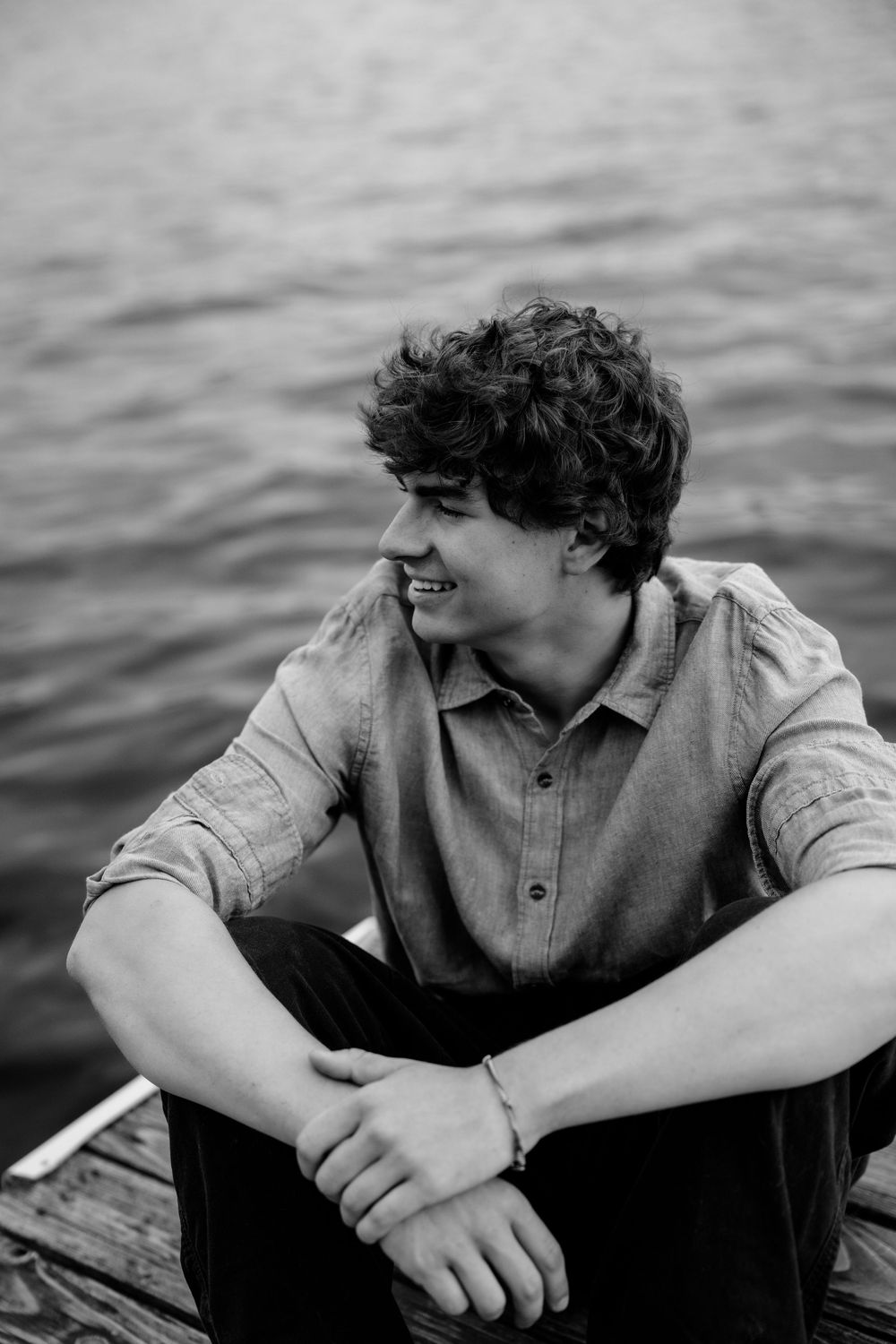 Black and white artistic photo series showing person in vest leaning on railing by water gazing off into distance.
