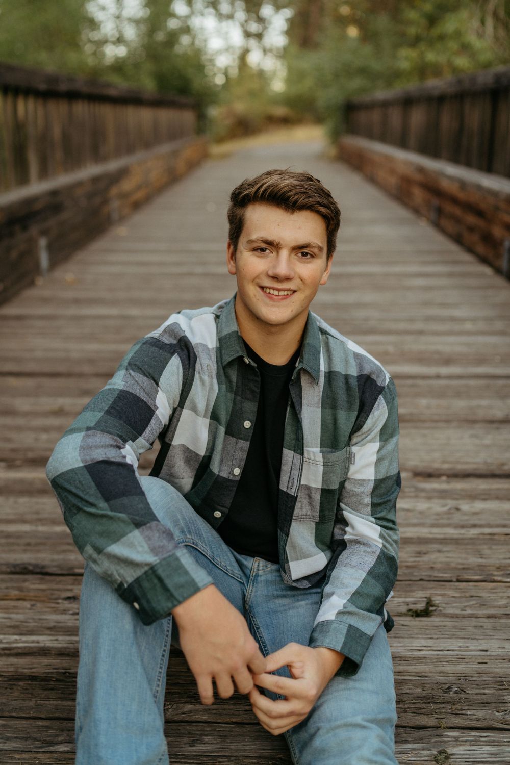 Portrait on a wooden bridge with trees and natural scenery in the background.