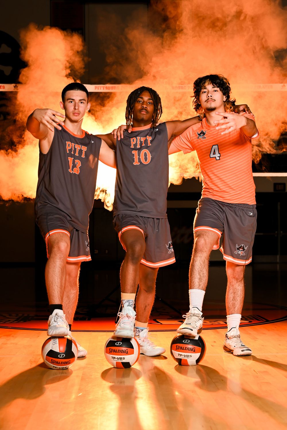 Athletes in Pitt uniforms show their sneakers against an orange-lit background.