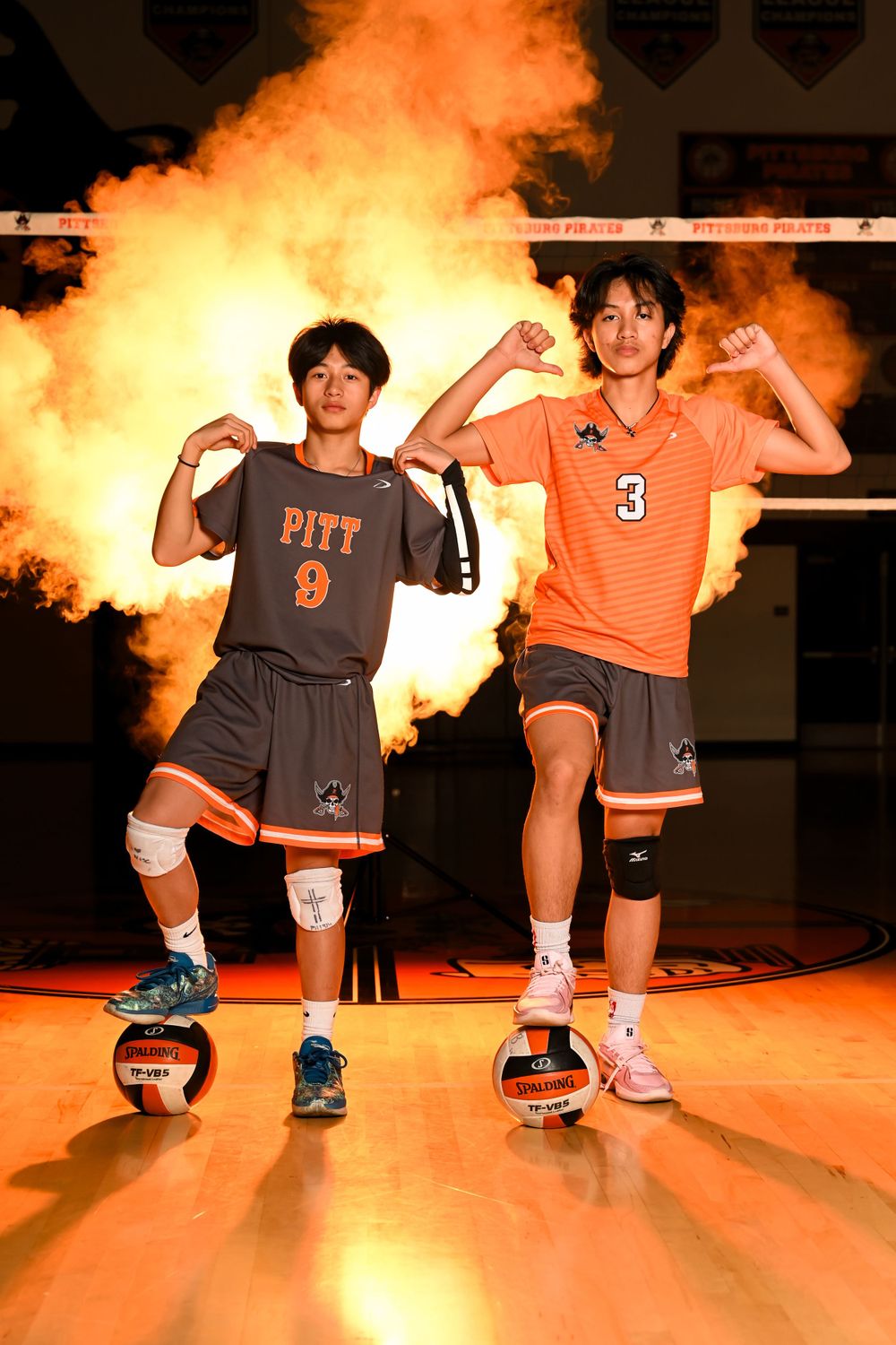 Basketball players in Pitt uniforms pose on a court with dramatic orange lighting.