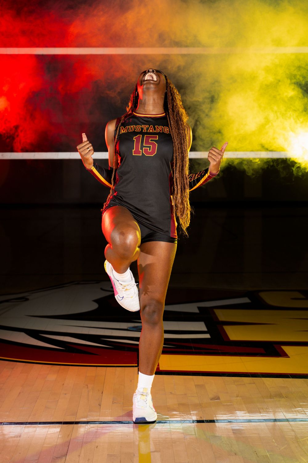 Athletic volleyball player in black jersey poses dynamically against colorful smoke backdrop.
