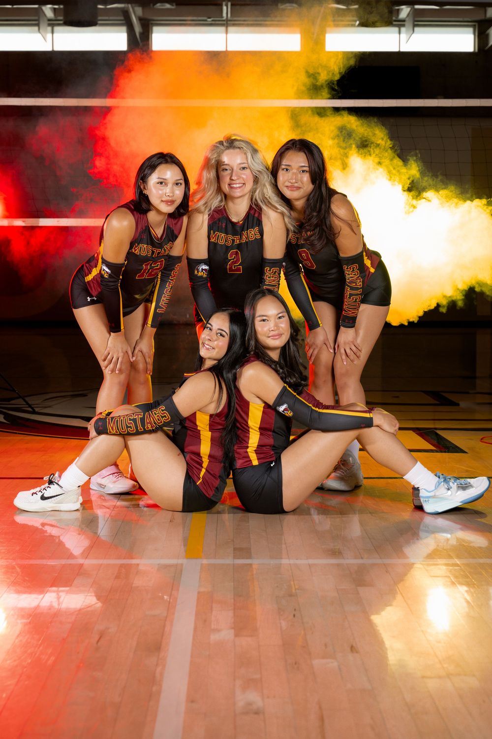 Volleyball team members pose together on gym floor with dramatic lighting effects.