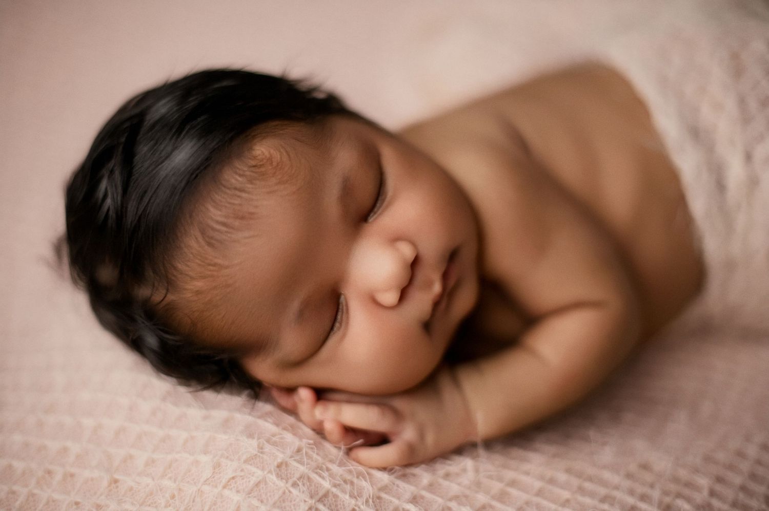 A peaceful sleeping newborn swaddled in olive green material against a dark green background.