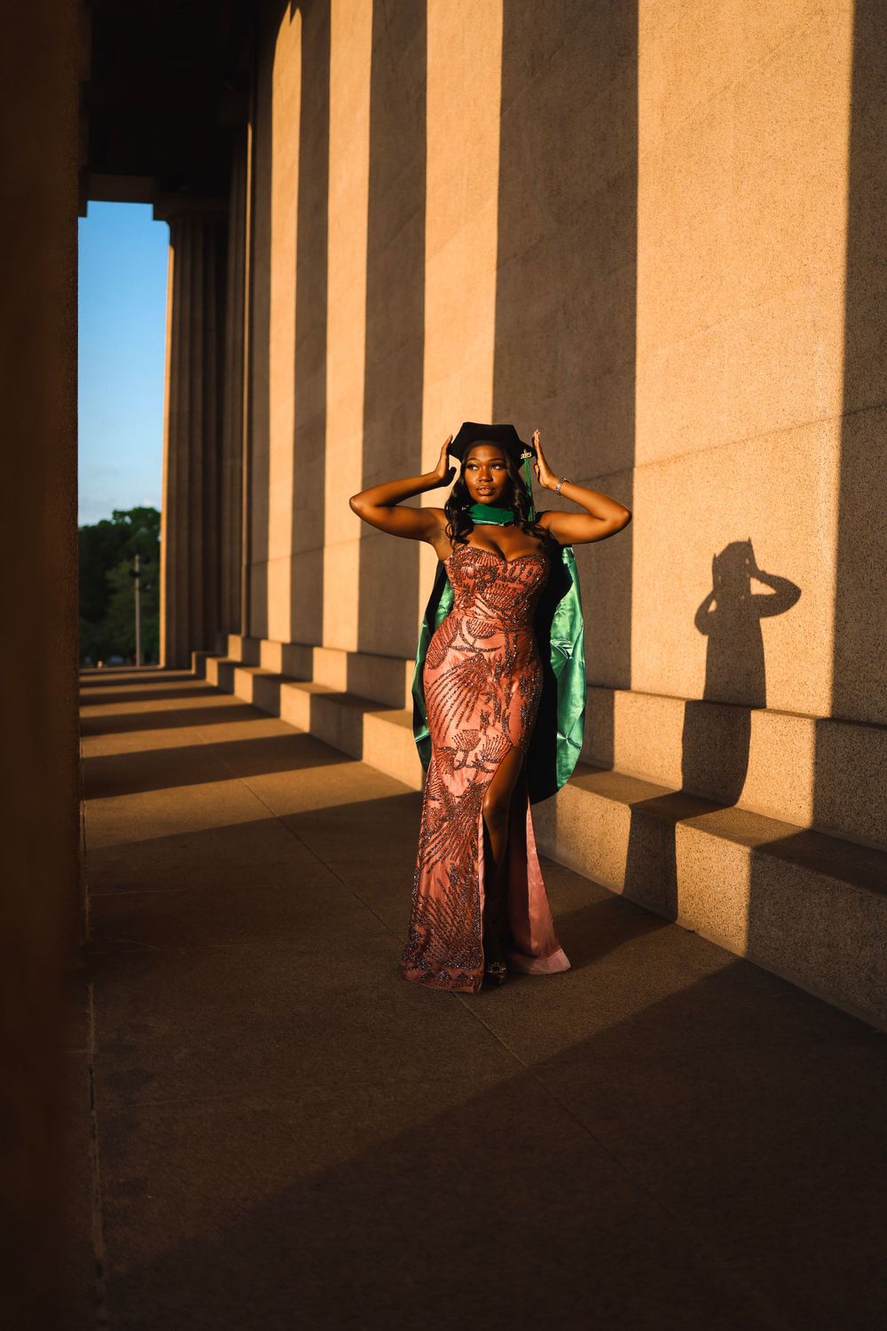 Elegant portrait in copper dress among architectural columns with sunset lighting.