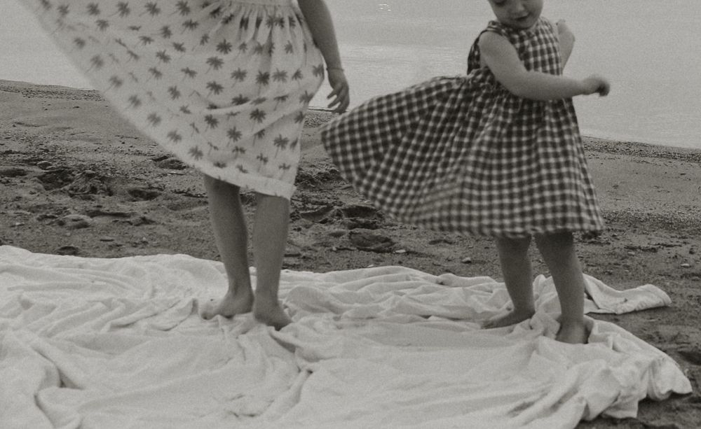 Black and white beach portraits with people sitting on a white blanket.