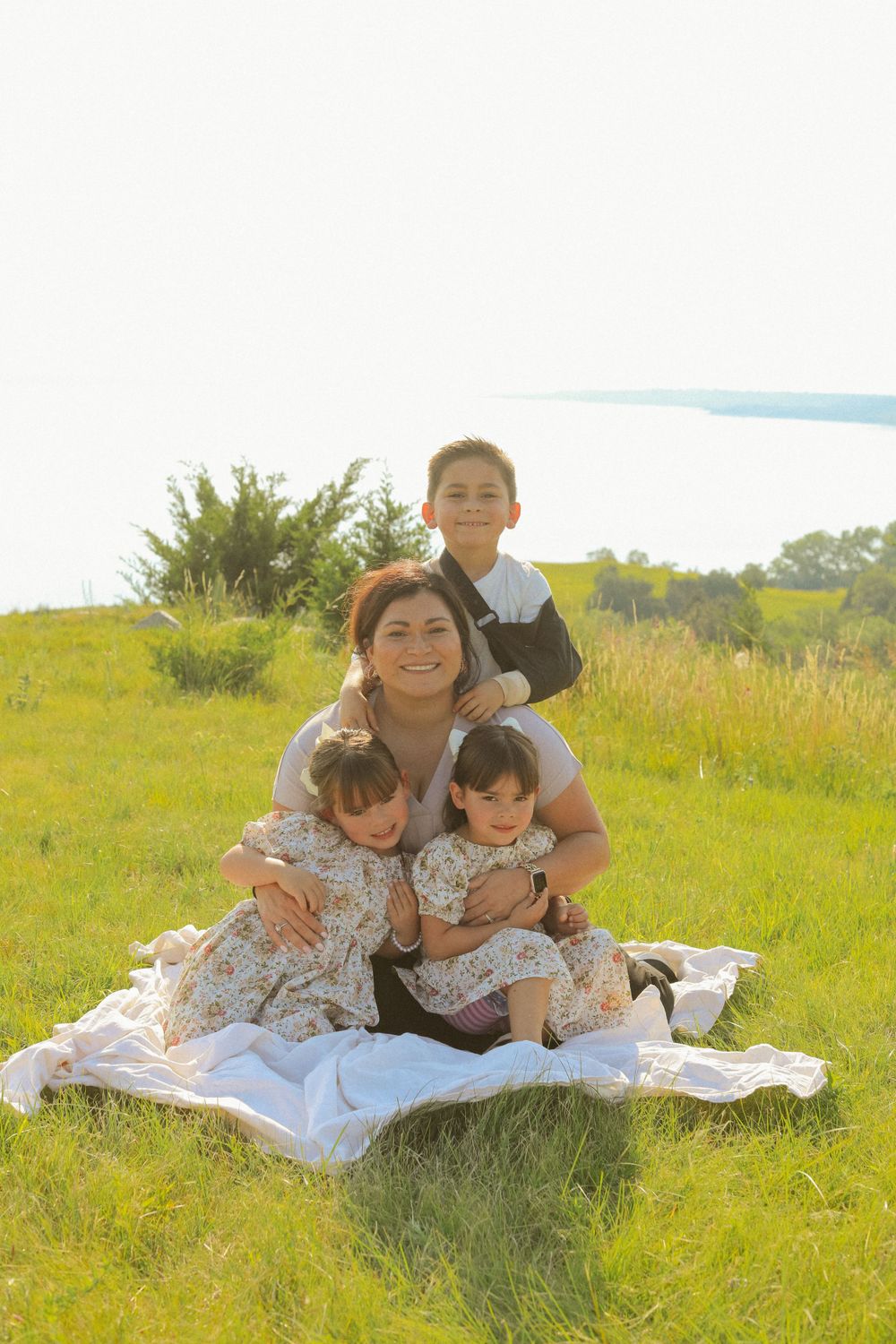 A group relaxes together on a blanket in a sunny meadow.