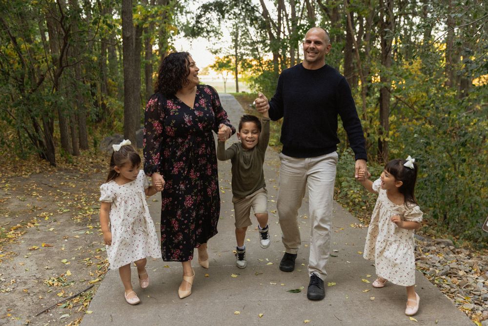 Family walking together on a tree-lined path during a fall photoshoot.