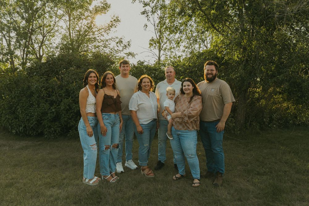 Group of friends posing together outdoors at sunset wearing casual denim and t-shirts.