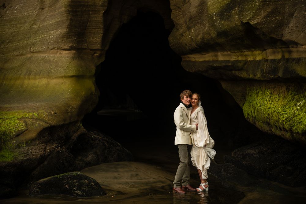 August and Vine wedding photography of bride and groom by the cave at maori bay auckland